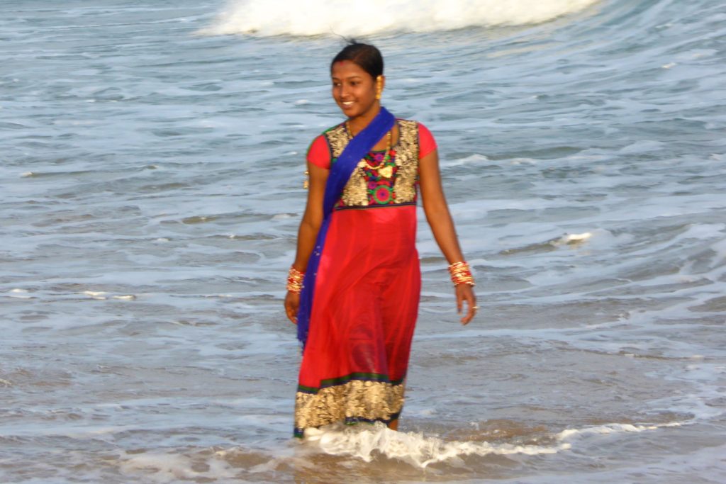 Kultur in Indien: mit Sari bekleidete Frau beim Baden im Meer. 