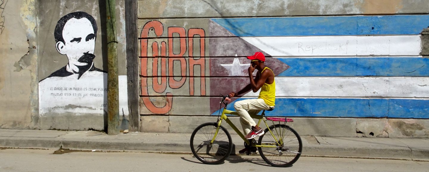 Santiago de Cuba. Radfahrer vor Wandmalerei.