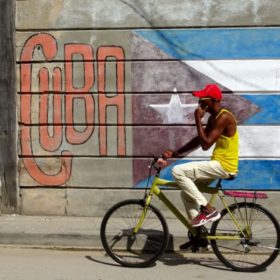 Santiago de Cuba. Radfahrer vor Wandmalerei.