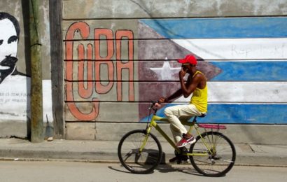 Santiago de Cuba. Radfahrer vor Wandmalerei.