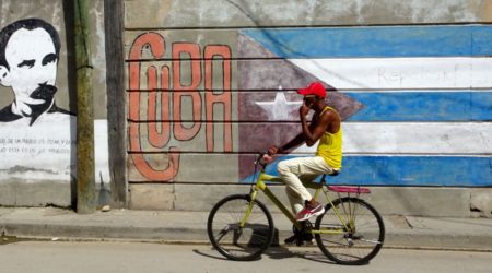 Santiago de Cuba. Radfahrer vor Wandmalerei.