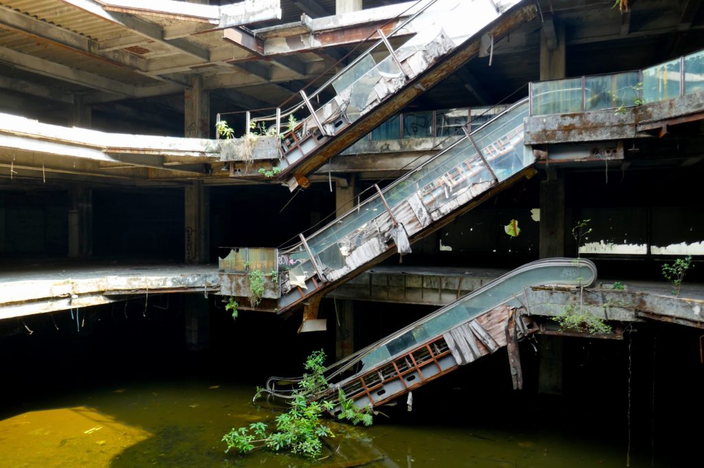 Lost Place New World Mall. Wasser im Untergeschoss, von oben fällt das Tageslicht in das Gebäude.