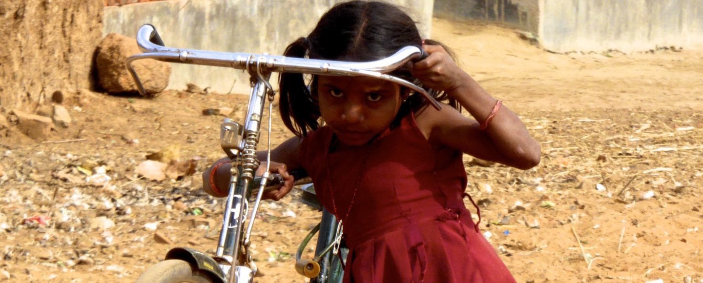 Street Photography in Indien. Kleines Mädchen mit großem Fahrrad.