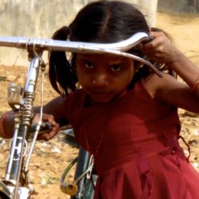 Street Photography in Indien. Kleines Mädchen mit großem Fahrrad.