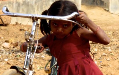 Street Photography in Indien. Kleines Mädchen mit großem Fahrrad.