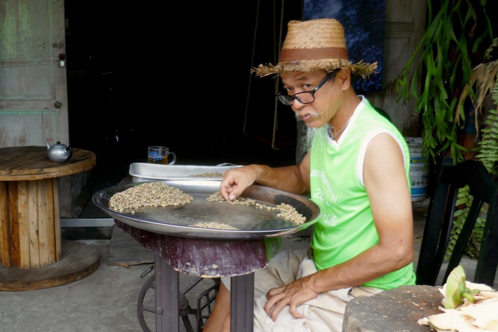 Menschen in Ranong. Mister Lek sortiert Kaffeebohnen.