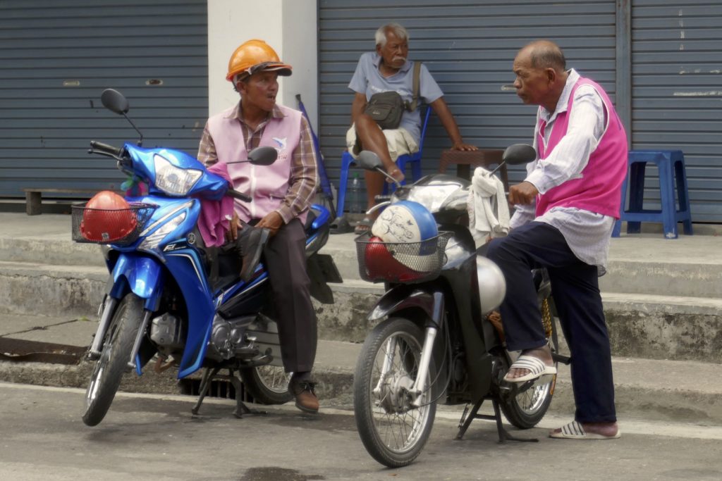 Menschen in Ranong. Wartende Motorrad-Taxifahrer.