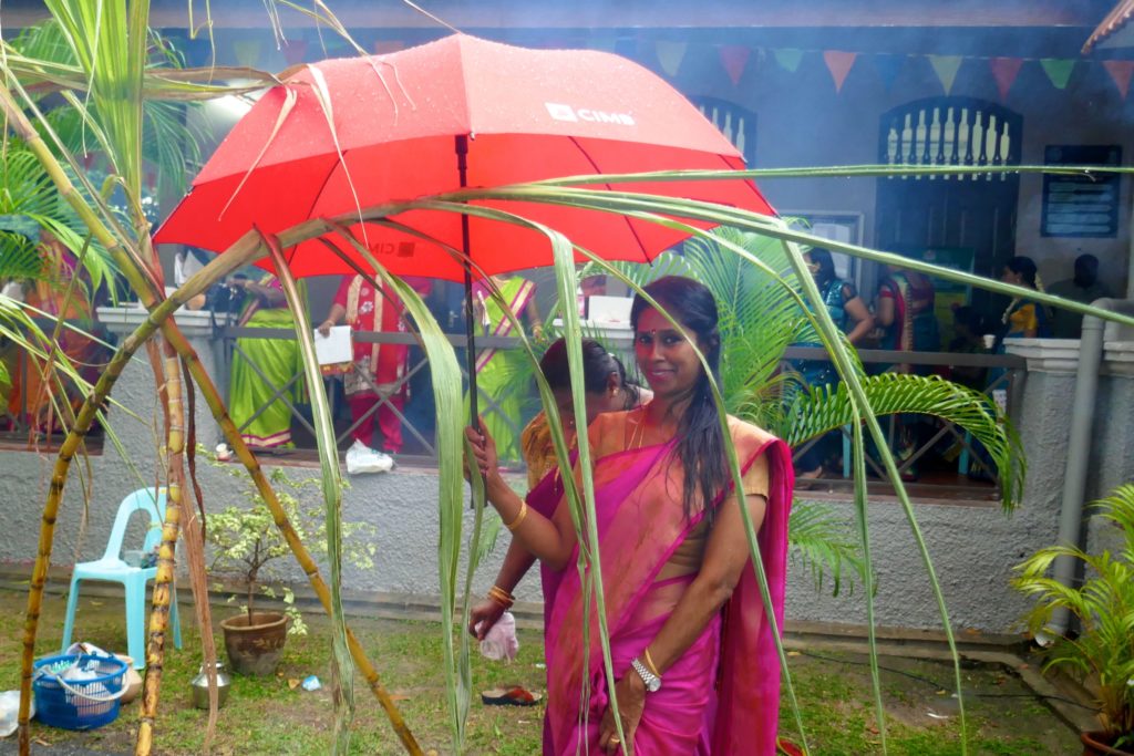 Pongal, indisches Erntedankfest in George Town, Malaysia. Frau mit Regenschirm.