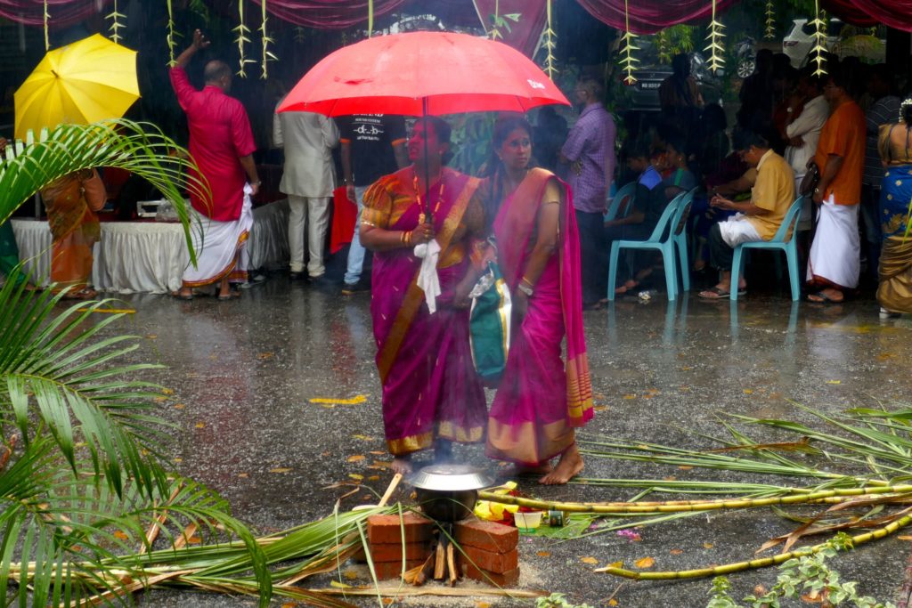 Behütung des köchelnden Reis, während es regnet, bei Pongal in George Town.