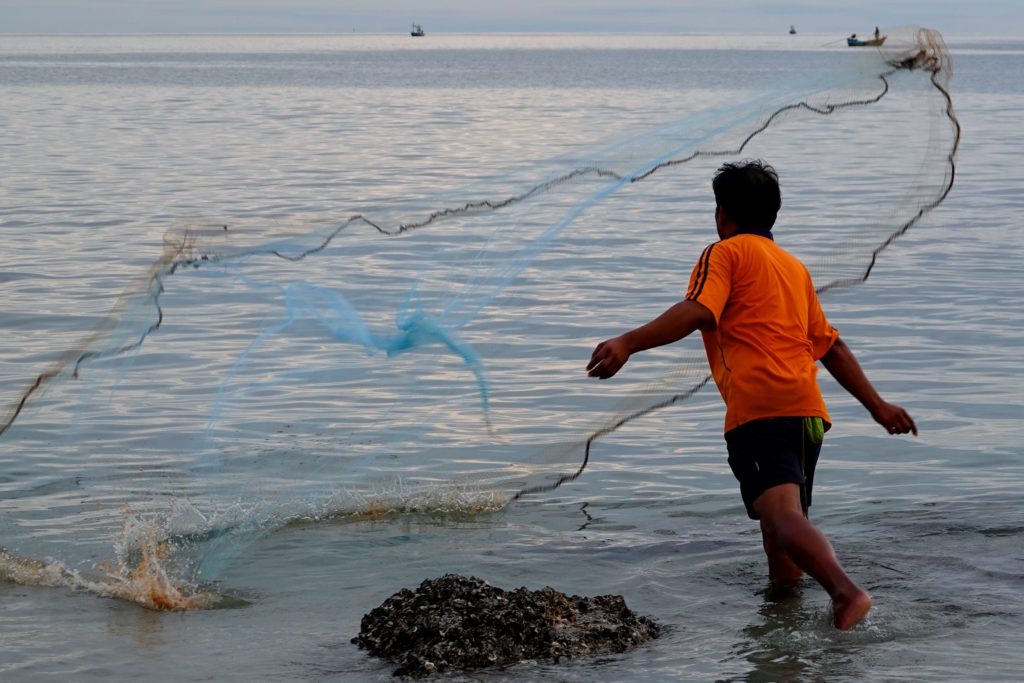 Fischer beim Auswerfen des Netzes an der Küste in Hua Hin.