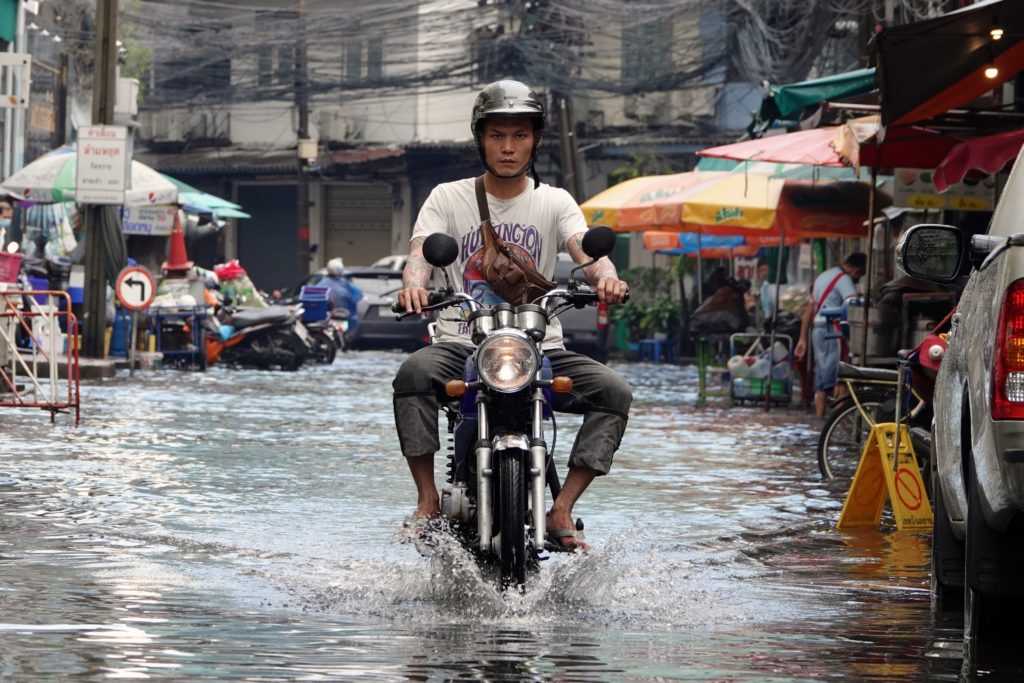 Regen in Bangkok. Mopedfahrer in Bang Rak.