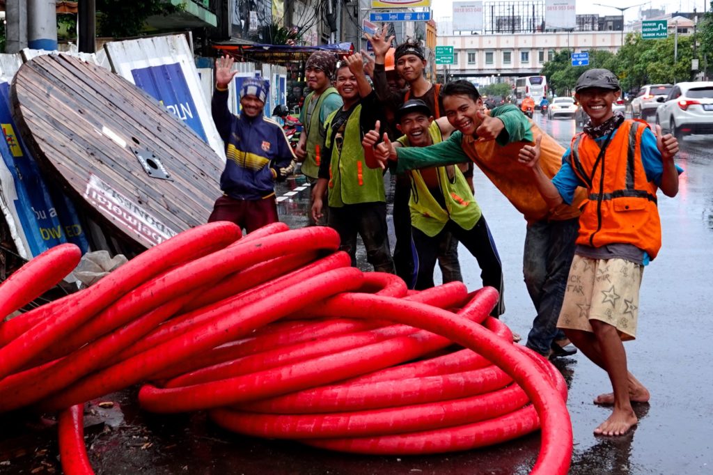 Gute Laune bei Regen: Straßenbauarbeiter in Jakarta.