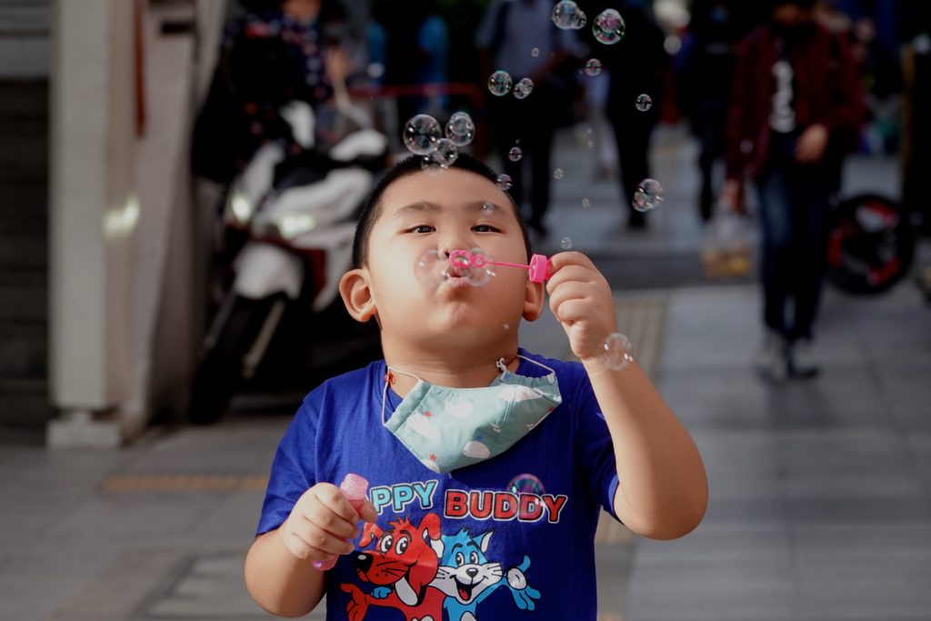 Auf der Straße in Bangkok: Junge bläst Seifenblasen. 