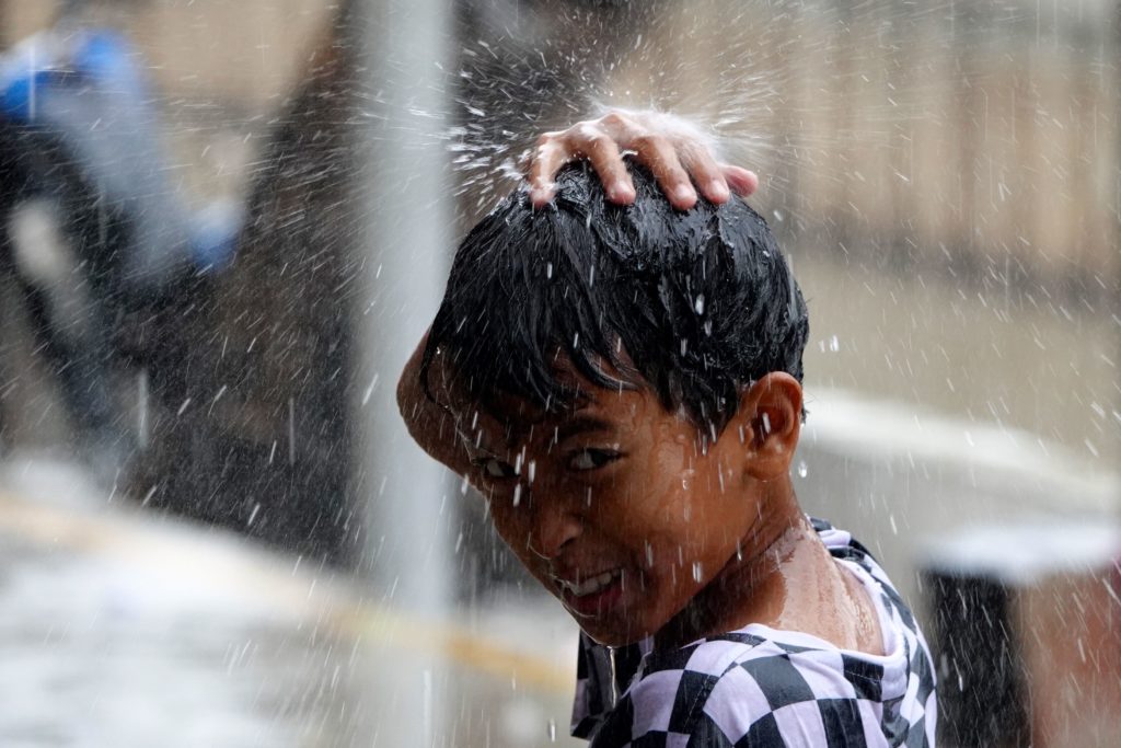 Regen in Jakarta, der Junge genießt es.