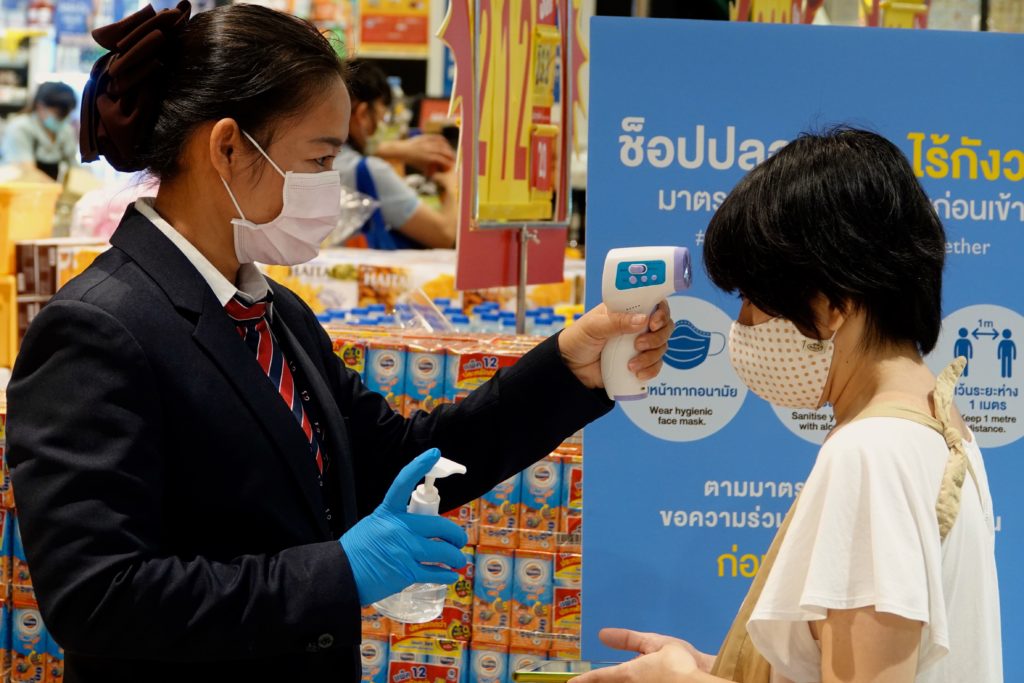 COVID-19: Check der Körpertemperatur und Desinfektion im Supermarkt in Bangkok.