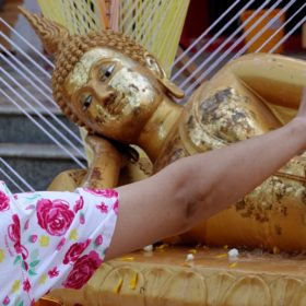 Songkran in Khon Kaen. Buddha-Figur wird im Tempel Phra Mahathat Kaen Nakhon mit Wasser übergossen.