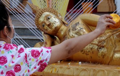 Songkran in Khon Kaen. Buddha-Figur wird im Tempel Phra Mahathat Kaen Nakhon mit Wasser übergossen.