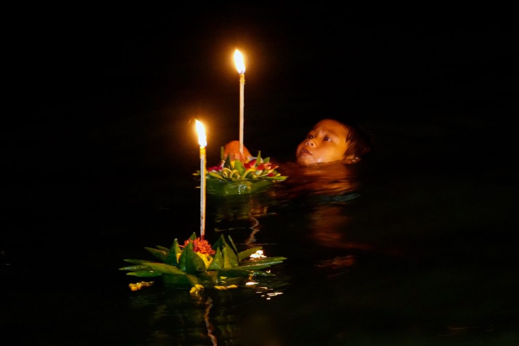 Seenomaden-Junge mit Krathong-Schiffchen im Wasser am Rawai Pier.