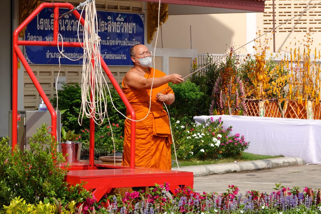 Songkran im Wat That von Khon Kaen: Mönch zieht an der Leine.