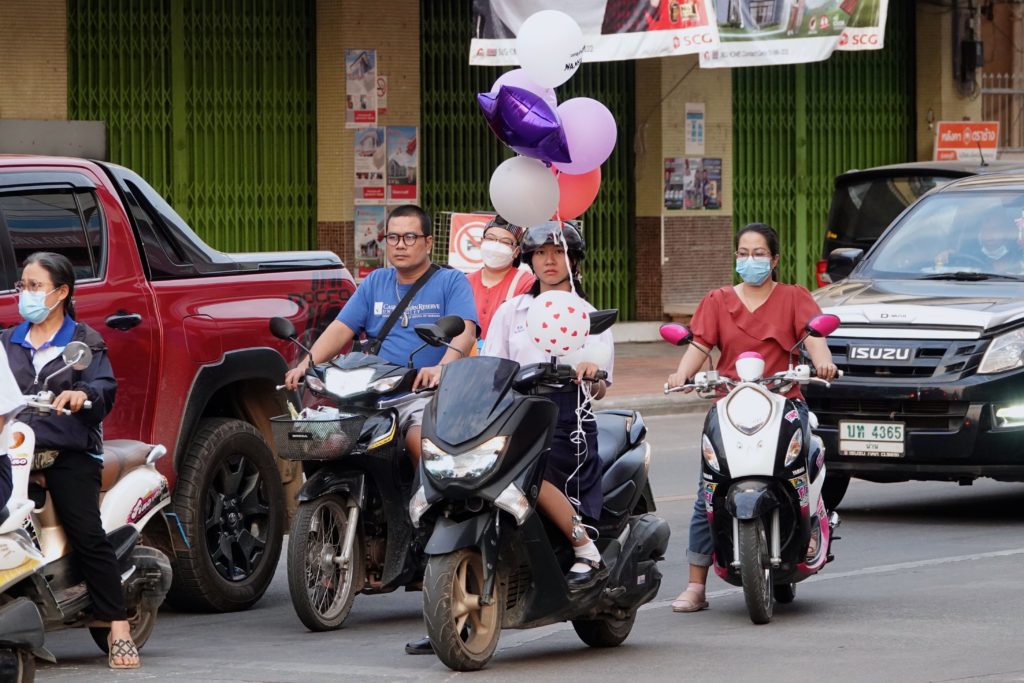 Valentinstagsnachzüglerin? Junge Frau auf Moped mit Ballons in Nan im Norden Thailands.