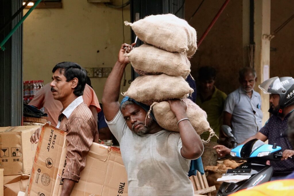 Lastenträger auf dem Pettah Market balanciert schwere Jutesäcke auf dem Kopf.