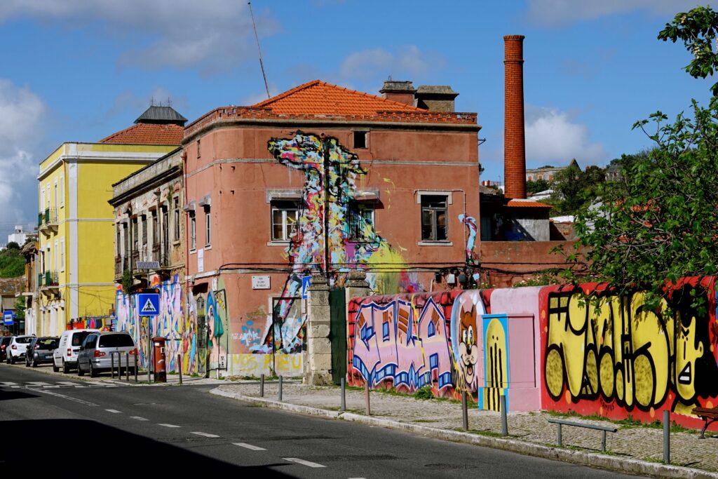 Straßenszene in Chelas mit Street Art auf historischen Gebäuden, Hundemotiv von Dario Silva