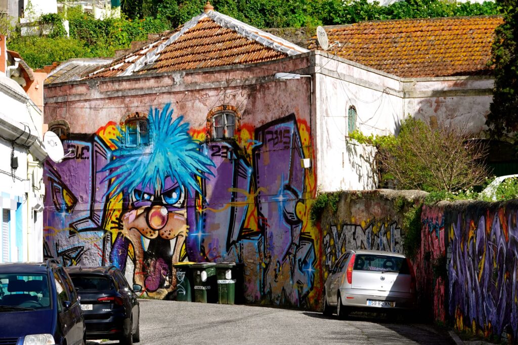 Violette Cartoon-Figur als Graffiti auf Wohngebäude im Chelas-Viertel