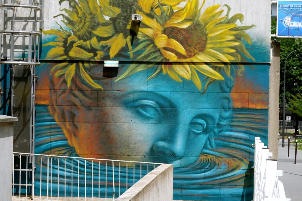 "Canicule" von Beau Stanton: Wandgemälde mit Sonnenblumen und blauem Gesicht als Kommentar zur Hitzewelle in Paris 13