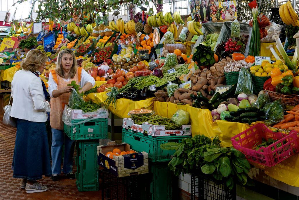 Obst- und Gemüsestand mit Verkäuferin und Kundin im Alvalade-Markt in Lissabon